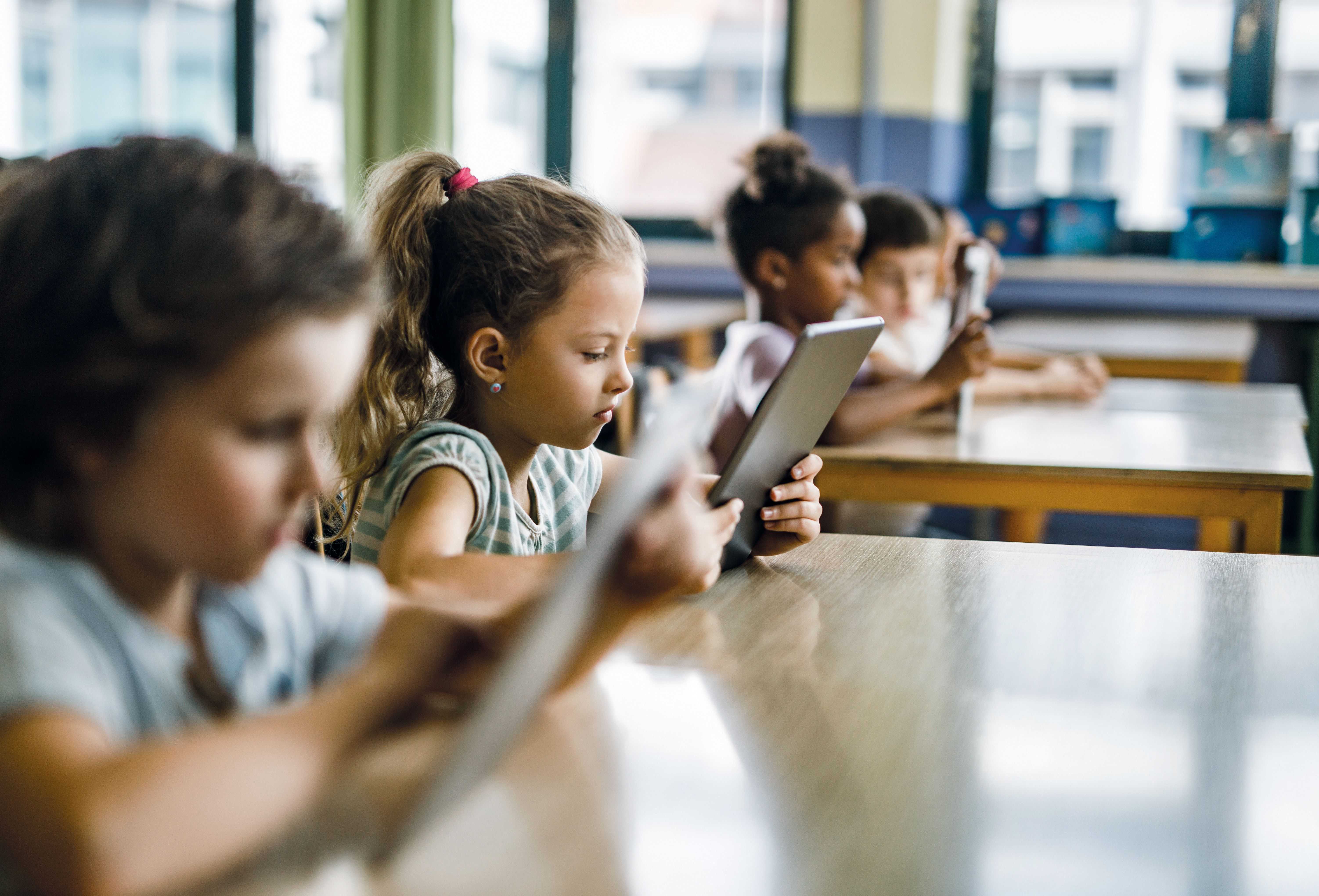 Kinder werden in einer Klasse gezeigt, jedes mit einem Tablet, darauf läuft die Geräteverwaltung Relution